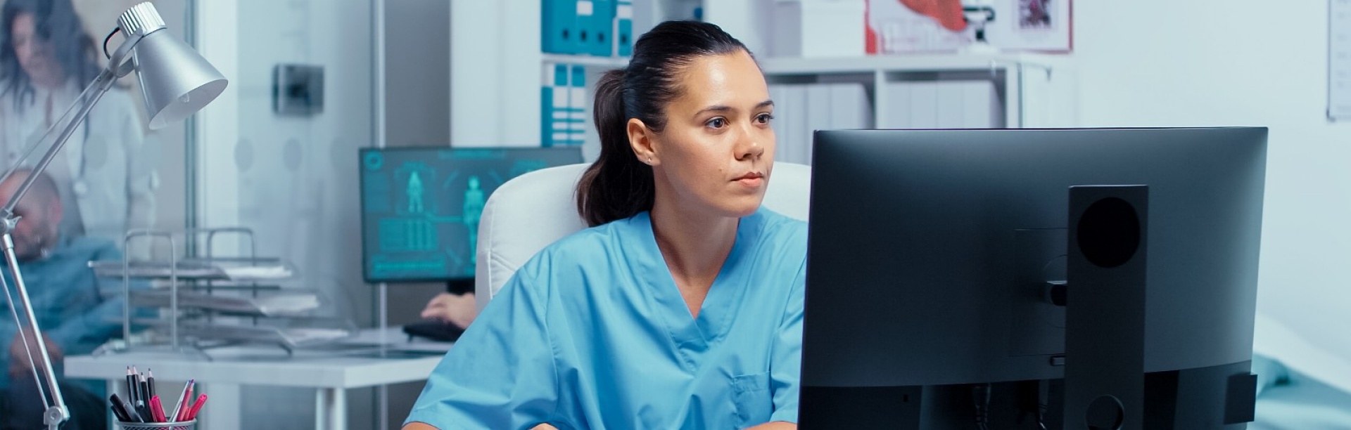 Nurse working on laptop at a desk. 