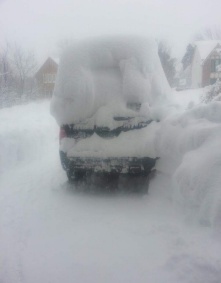 car with pile of snow on top. 