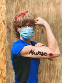 Nursing alumni Cari Gavin flexing her arm, which has the word nurse painted on it, like Rosie the Riveter. 