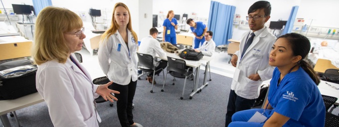 Zoom image: nursing instructor with students in lab.
