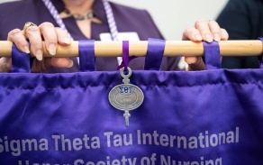 Zoom image: The 2021 Chapter Key Award lays on top of the Sigma Theta Tau flag. 