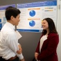 Zoom image: Students talking about research poster.