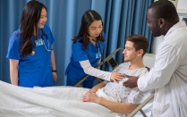 Zoom image: Teacher shows students how to use stethoscope.