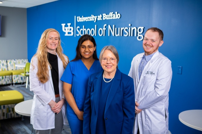 Nursing students in scrubs and white coats with the dean. 
