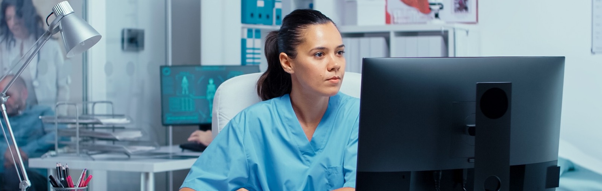 Nurse working on laptop at a desk.