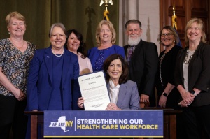 Dean Wysocki with Kathy Hochul and New York State education leaders holding signed legislation document. 