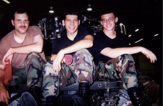 Three US military servicemembers sitting in a helicopter. 