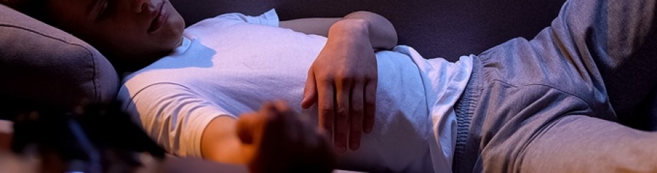 Teen sleeping on a couch in the dark.